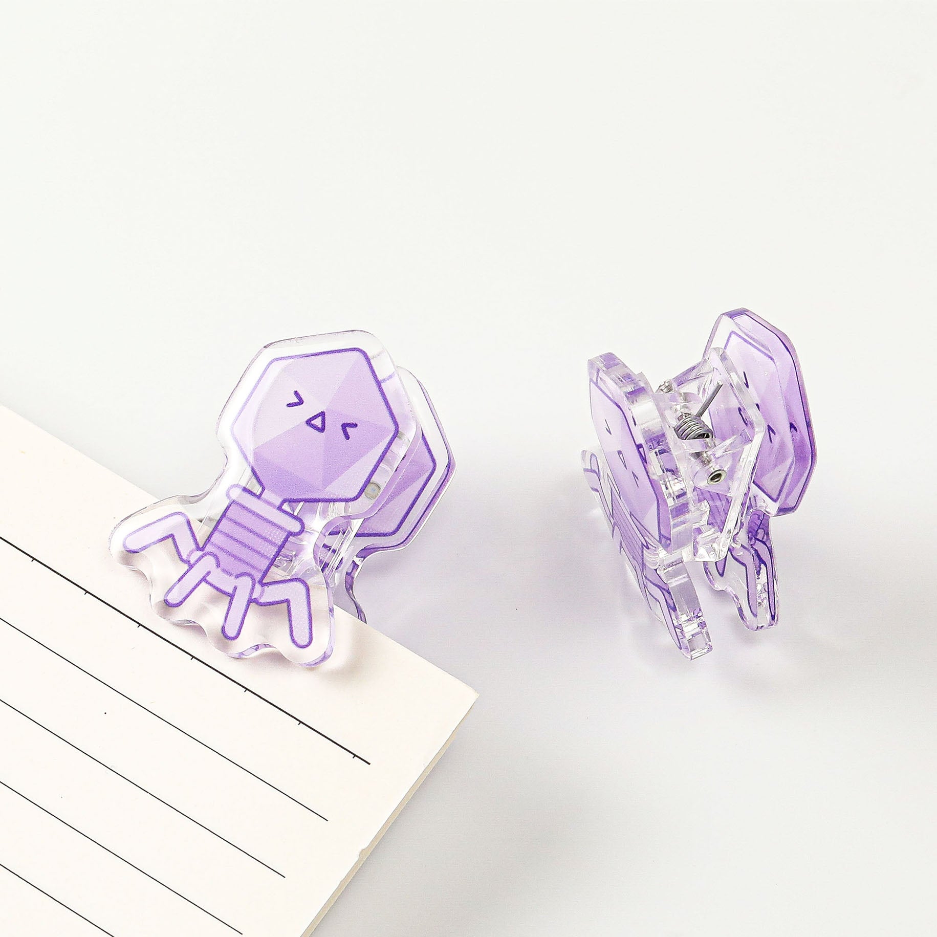 Virus-inspired acrylic stationery clip with a smiling bacteriophage design, a fun science-themed accessory for organizing everyday paperwork.
