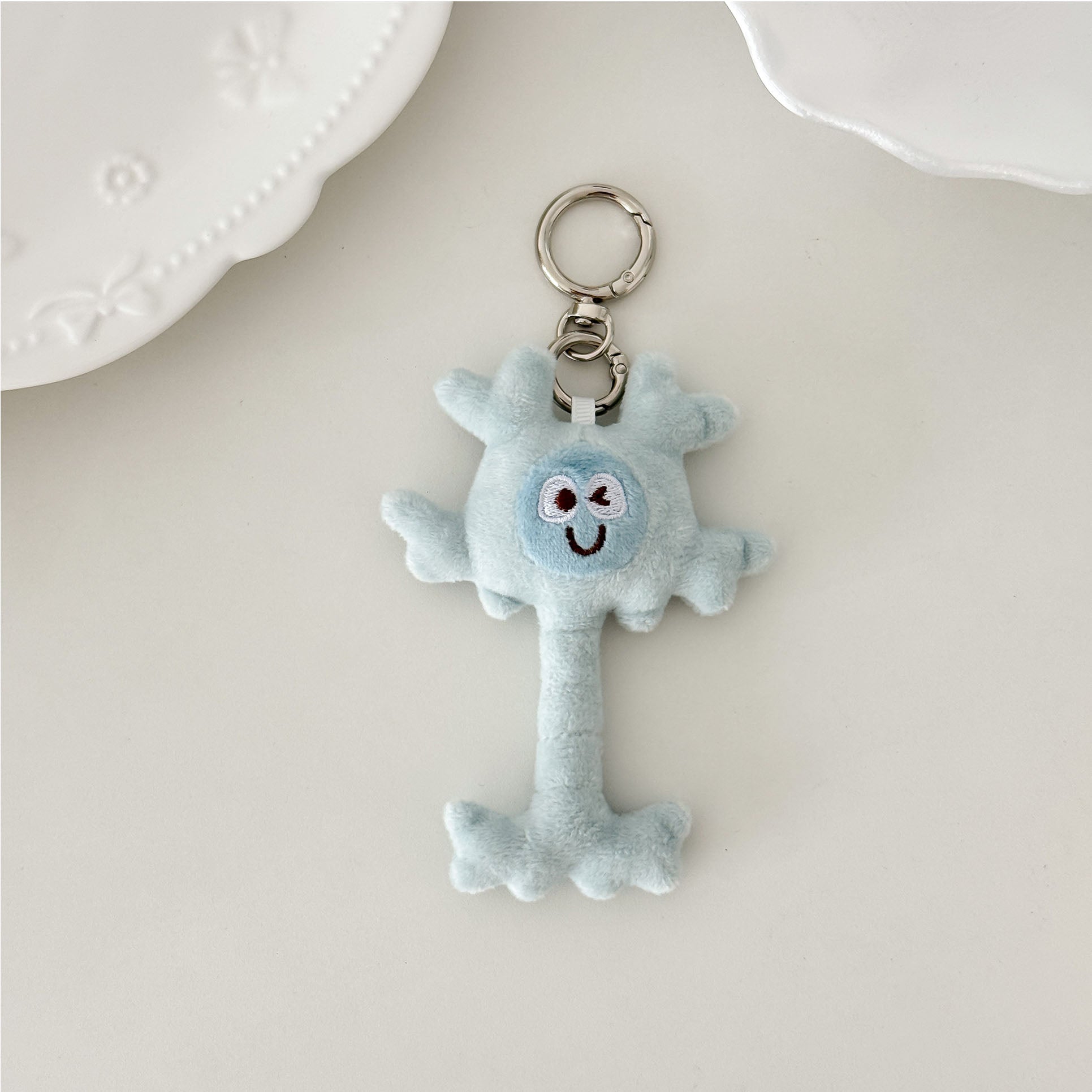 Cartoon neuron plush keychain in light blue with embroidered details and premium key ring.
