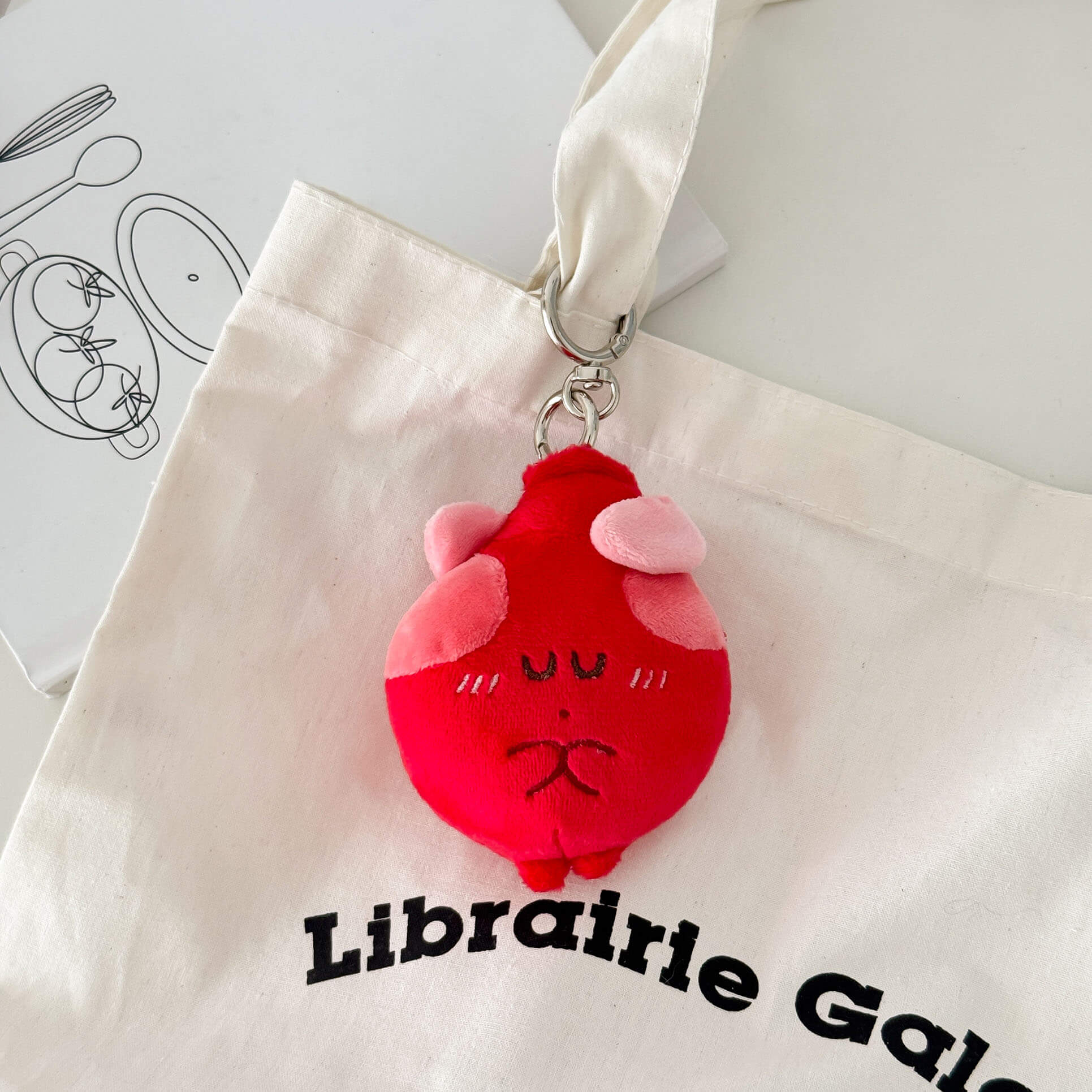 Heart-shaped plush keychain with embroidered features and soft stuffed organ design.