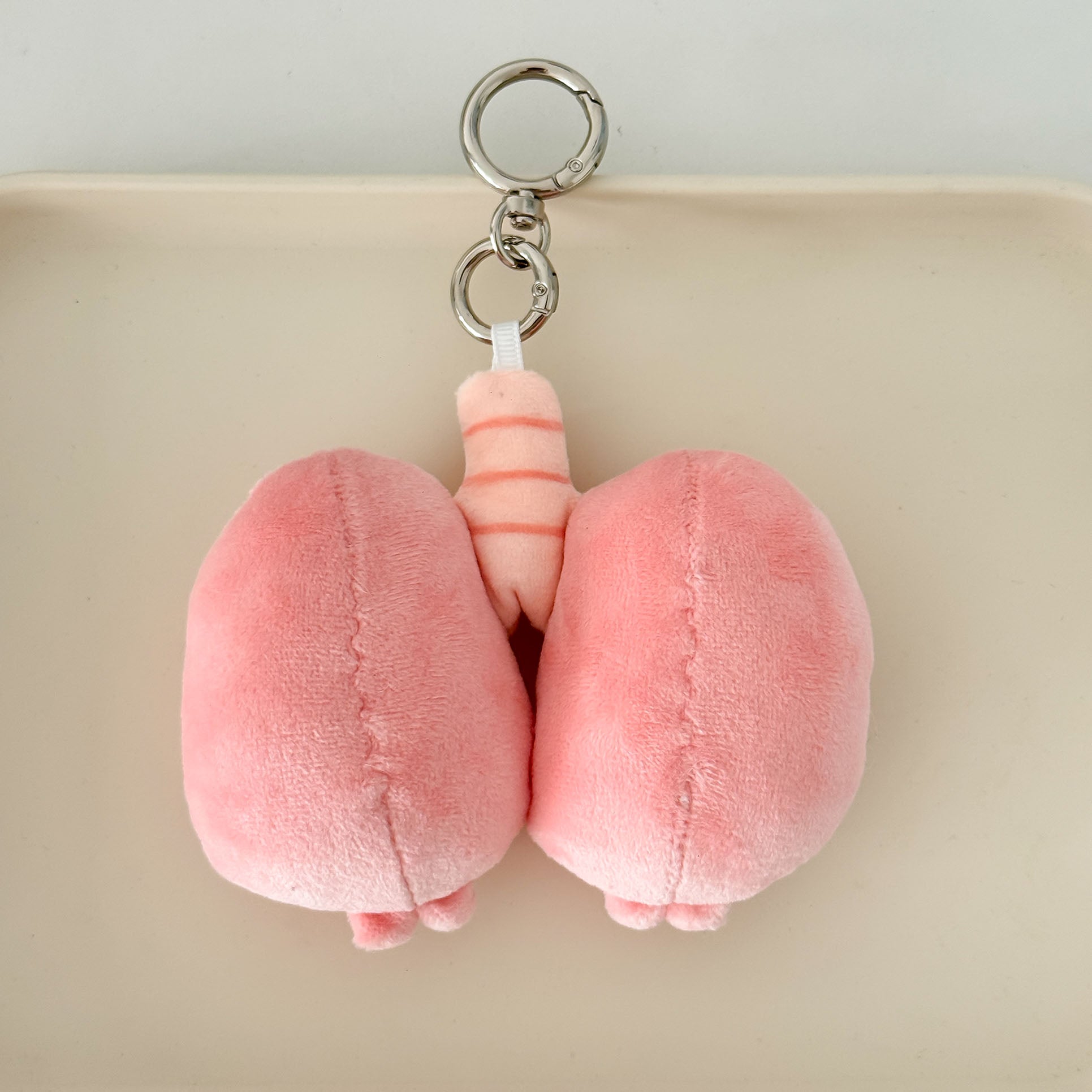 Pink respiratory lung plush keychain with embroidered facial features and lightweight design.