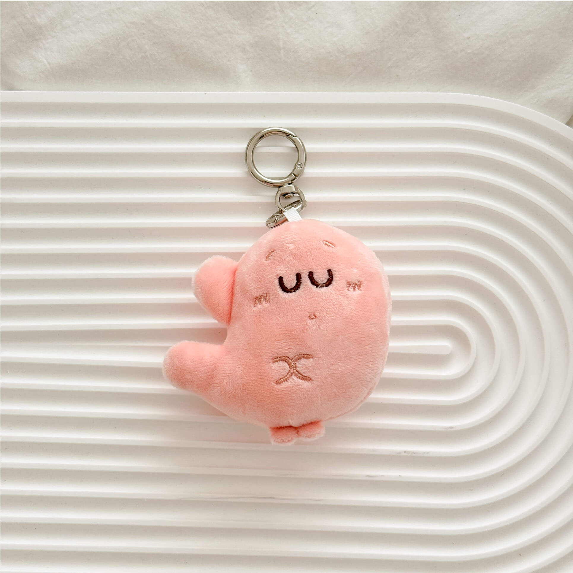 Soft pink stomach organ plush keychain featuring a expression and durable metal keychain clasp.