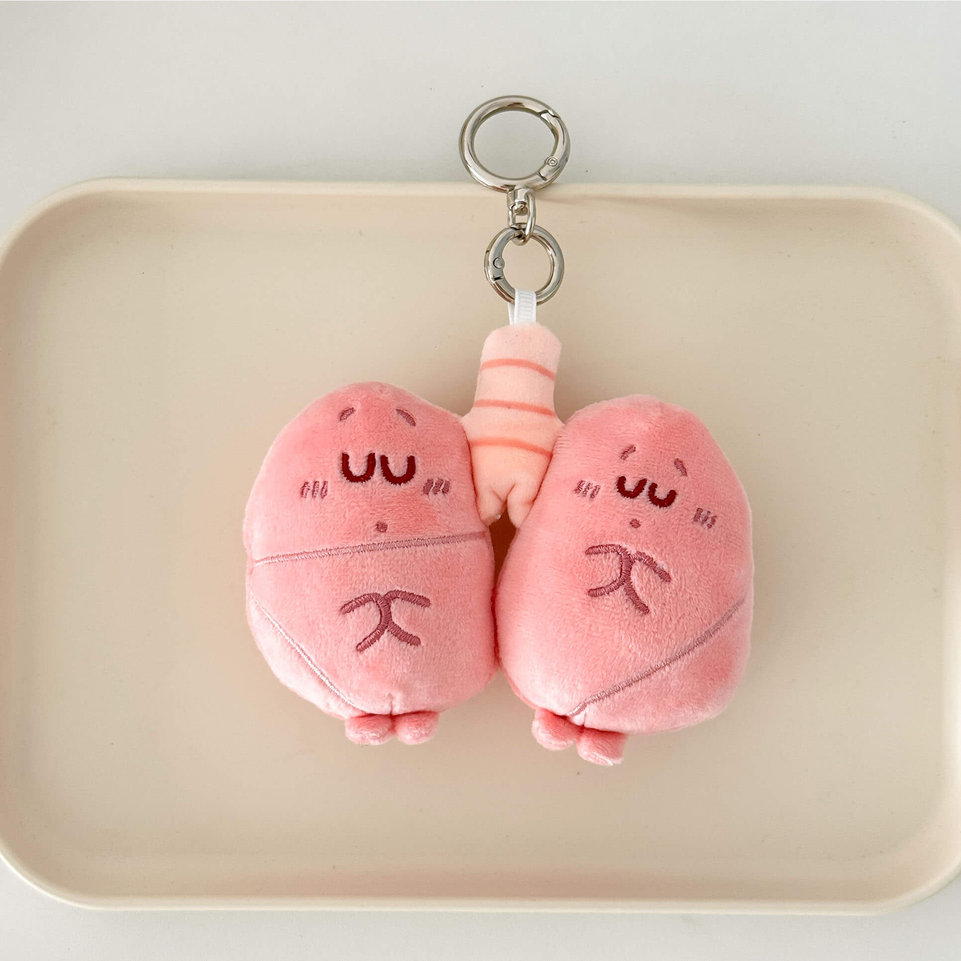 Cartoon lung plush keychain in pastel pink with embroidered details and premium key ring.