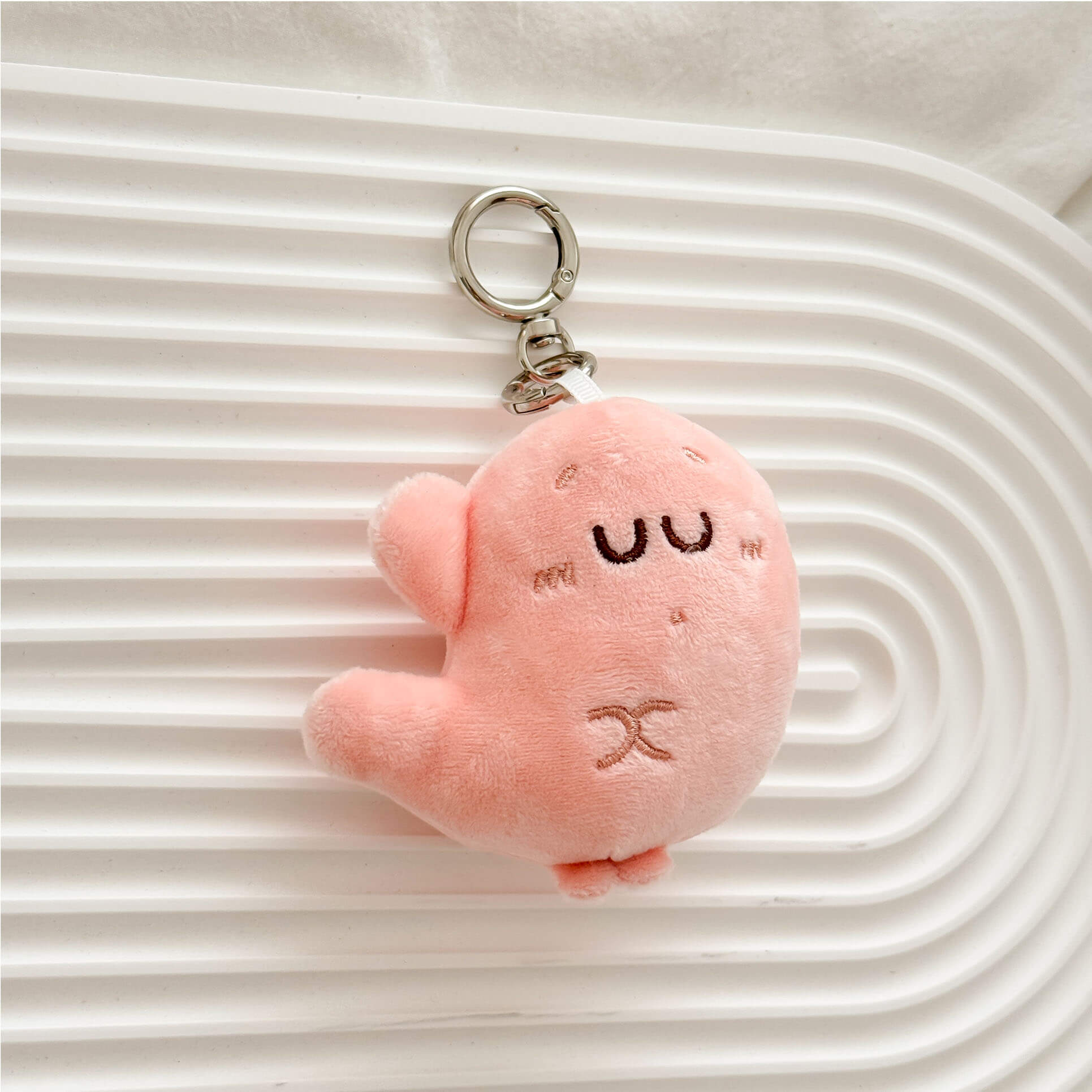 Cartoon stomach plush keychain in pastel pink with embroidered details and premium key ring.