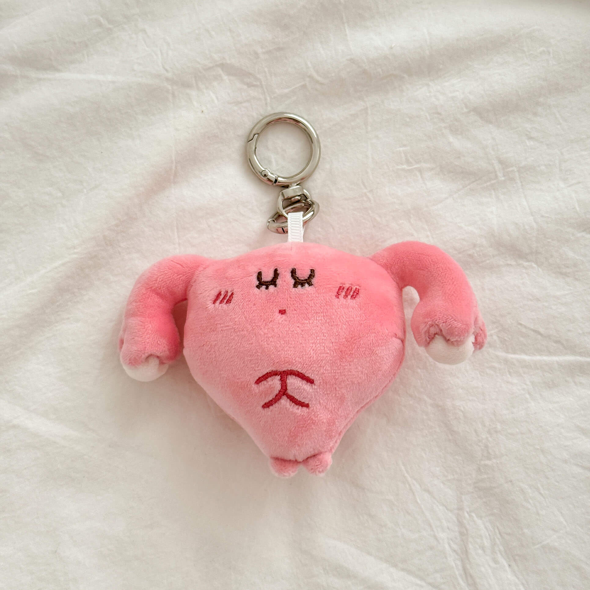 Cartoon uterus plush keychain in pastel pink with embroidered details and premium key ring.